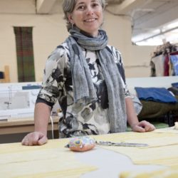Senior clothing designer and artist poses at her work space in fiber arts studio